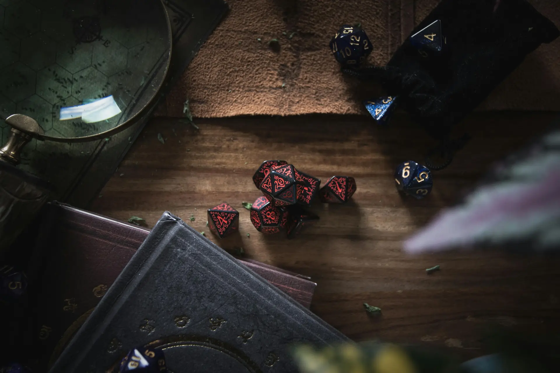 Set of red and blue polyhedral dice on a wooden table beside TTRPG rulebooks, representing dice mechanics and storytelling design.