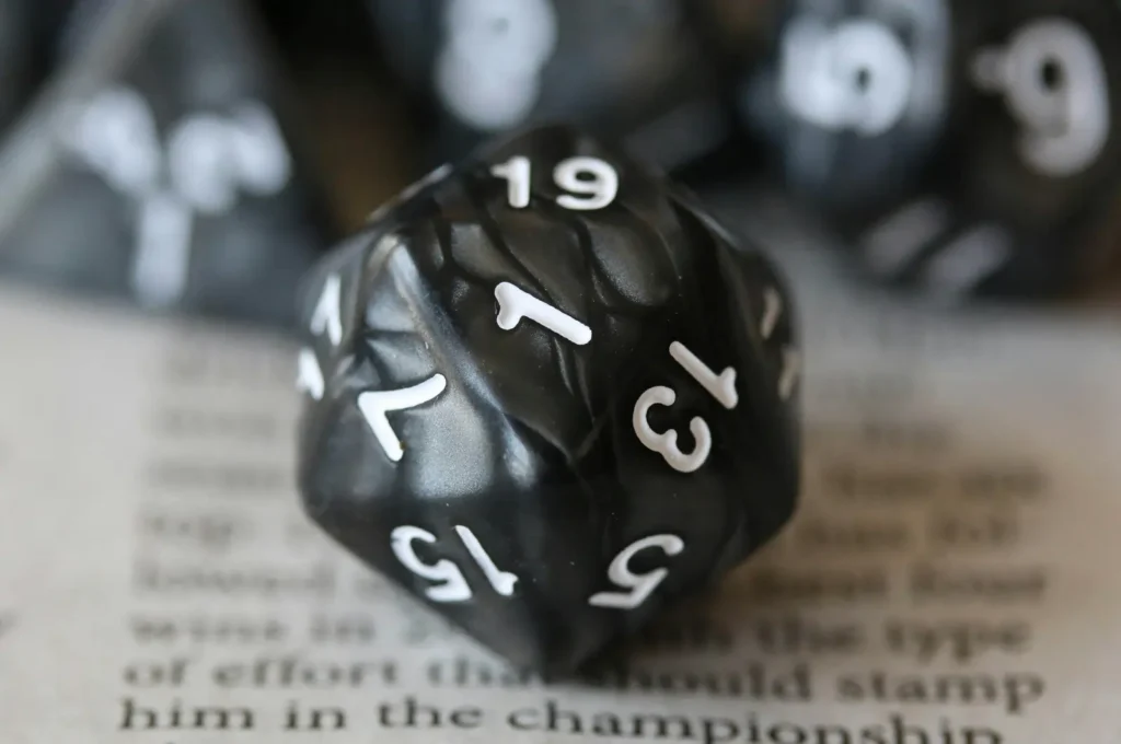 D20 Dice and Narrative Tension in Tabletop RPGs Close-up of a black D20 die resting on a book page, symbolizing narrative tension and chance in TTRPG dice systems.