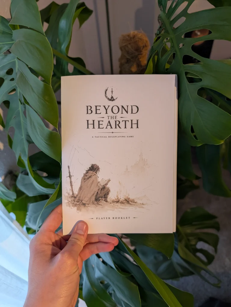 The beyond the hearth ttrpg player booklet held in hand in front of a plant.